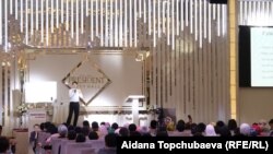 Максат Муктаров аудитория алдында сүйлөп жатат.