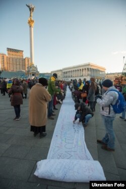 Учасники мітингу за євроінтеграцію на майдані Незалежності в Києві підписують лист президентові на полотні