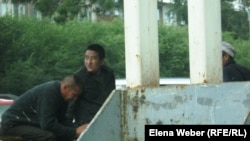 Оралманы сидят у городского рынка Темиртау.   