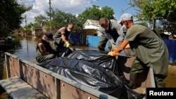 Ыктыярчылар жана муниципалдык кызматкерлер Голая Пристань шаарындагы  суу астында калган үйлөрдөн сөөктөрдү алып чыгууда. Сүрөт 2023-жылдын 16-июнда тартылган. 