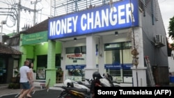 Іноземні туристи намагаються обміняти гроші в пункті обміну валют на острові Балі, Індонезія, архівне фото, 2019 рік