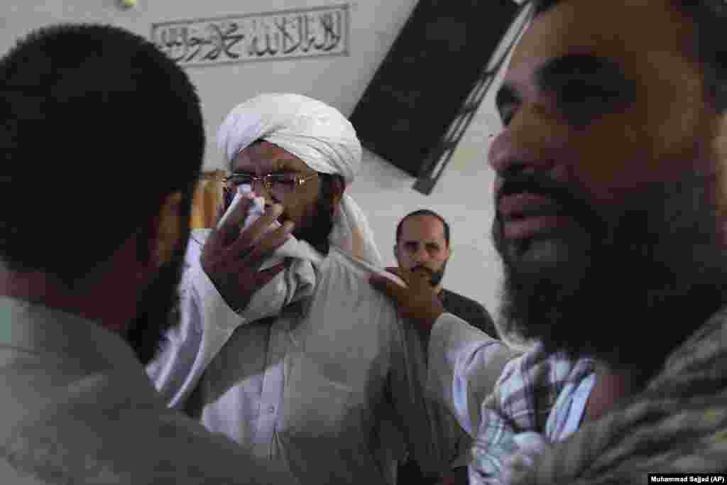 Люди втішають священнослужителя, який оплакує загибель студентів у медресе