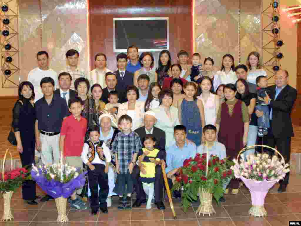 Большая семья Сарсенбаевых на юбилее родоначальника. Отцу Алтынбека Сарсенбаю  90 лет. Алматы, 25 июля 2004 года.  -  Большая семья Сарсенбаевых на юбилее родоначальника. Сарсенбаю-ата 90 лет. А. Сарсенбаев во втором ряду справа. Он держить на руках внучатого племянника Димаша. Алматы, 25 июля 2004 года. 