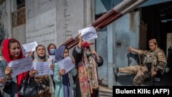 «Talyban» söweşijisi Kabuldaky Aýallaryň işi baradaky öňki ministrligiň öňünde, aýallaryň kanuny hukuklaryny ýokarlandyrmagy talap edýän demonstrasiýa wagtynda, owgan aýallarynyň plakatlaryna syn edýär. 2021-nji ýylyň 20-nji sentýabry.