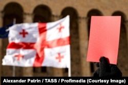 Активіст піднімає червону картку на знак протесту біля будівлі парламенту після інавгурації Міхеїла Кавелашвілі, шостого президента Грузії. Тбілісі, 29 грудня 2024 року