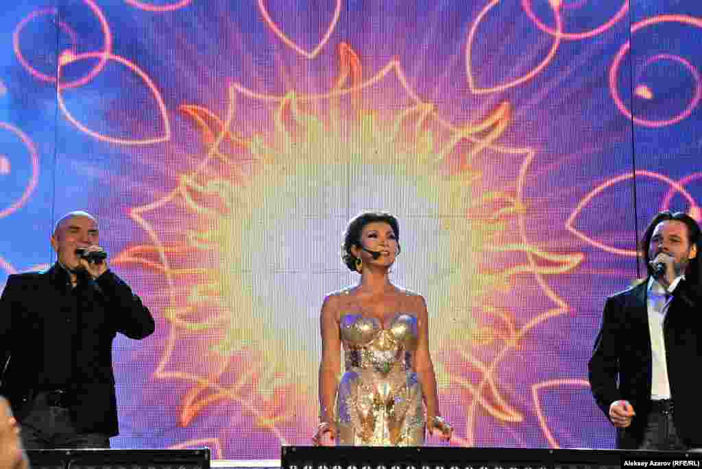 Две песни от Дариги Назарбаевой &nbsp; Обращаясь к собравшимся, Дарига Назарбаева напомнила, что является артисткой и знает, что такое выход на сцену. За время 14-го фестиваля на сцену она выходила дважды. Собственно, как и на предыдущих двух ретрофестивалях, на которых побывал репортер Азаттыка. Сначала исполнила вместе с российской арт-группой &laquo;Хор Турецкого&raquo; казахскую песню &laquo;Наз қоныр&raquo;. При этом нельзя было не заметить, что во время ее пения на монитор за ее спиной проецировалось изображение солнечного светила.