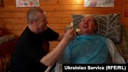Vitaliy Shumey smiles and speaks to his father, Serhiy, who has been by his son's side since he was wounded in August 2022. The Ukrainian soldier has been recovering in the western city of Truskavets and has regained his ability to speak.