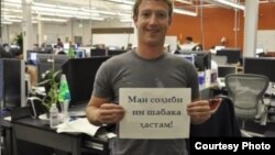 Facebook founder and CEO Mark Zuckerberg with a sign in Tajik: "I own this network."