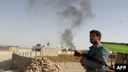 An Afghan policeman stands guard as smoke rises from the site of a bomb attack last month in Ghazni Province. (file photo)