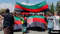 Люди несут национальный флаг во время акции протеста, прошедшей в День независимости Афганистана в Кабуле, 19 августа 2021 года