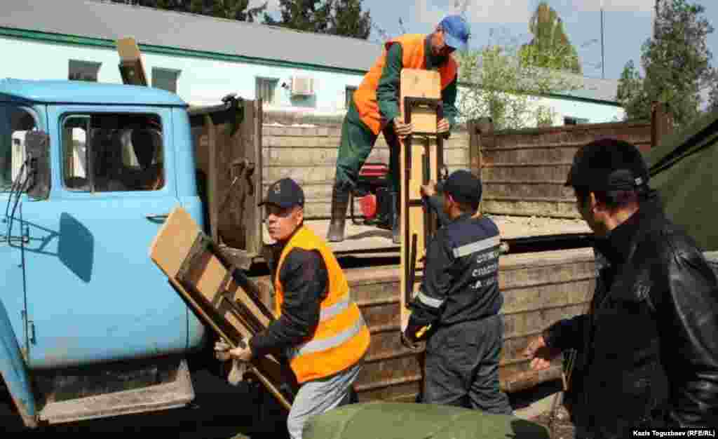 Сотрудники службы спасения выгружают скамейки для погорельцев. 