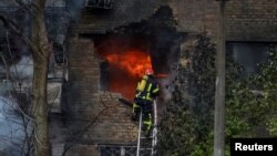 A firefighter works to put out a fire at a residential building hit by a Russian missile strike in Kyiv on November 15.
