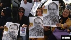 Під час виборчої кампанії в Ірані прихильники тримають плакати з зображенням кандидата Могаммада Багера Галібафа
