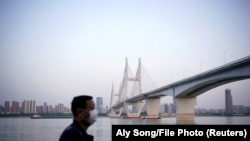 Чоловік, що носить маску для обличчя, биля річки Янцзи в Ухані після того, як було знято карантин в Ухані, столиці провінції Хубей, епіцентрі нової коронавірусної хвороби в Китаї.