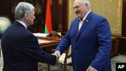 ABŞ prezidentinin nümayəndəsi Con Koul və Belarus prezidenti Aleksandr Lukaşenko Minskdə görüş zamanı əl sıxırlar.