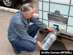 Ludovic, în timp ce își alimentează bidoanele de la un recipient public.