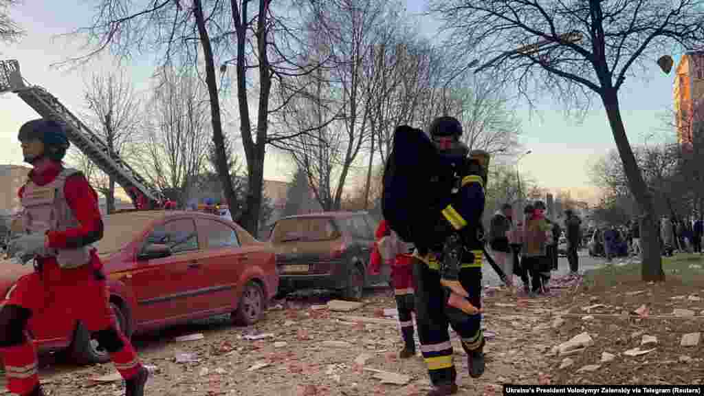 Ратавальнік нясе чалавека каля дому, па якім ударыла расейская ракета