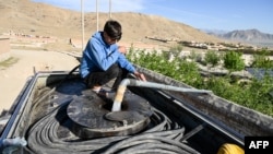 Əfqan oğlan Kabilin kənarındakı quyudan çəni içməli su ilə doldurur.