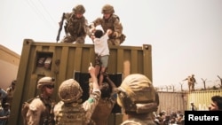 سربازان امریکایی در حال کمک به یک طفل افغان در میدان هوایی بین المللی کابل 