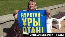 Зағип әйел Қазына Махмедова "Нұр Отан" партиясына наразылық жазылған плакат ұстап  Астананың орталығындағы алаңда отыр. 12 қыркүйек 2013 жыл.