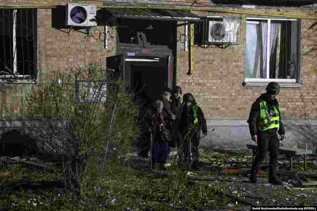 Рятувальники допомагають літній маломобільній жінці дістатися з будинку після російського удару. Київ, 29 листопада 2025 року