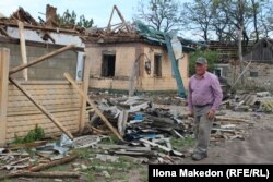 Житель Новопавлівки Микола Макарович біля сусідського розбитого російськими атаками будинку, травень 2025 року