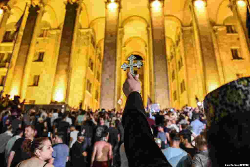 Священник держит крест над группой протестующих во время шествия против приезда российского депутата в Тбилиси. Грузия, 21 июня. (Dato Koridze, RFE/RL)