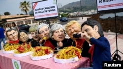 Протестувальники у масках лідерів країн G7 «їдять» лапшу біля місця проведення саміту на Сицилії, Італія, 25 травня 2017 року