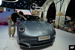 Рабочий протирает Ora, электромобиль китайского бренда, во время Шанхайского автосалона 2023 года в Национальном выставочном и конференц-центре в Шанхае, Китай, 18 апреля 2023 года