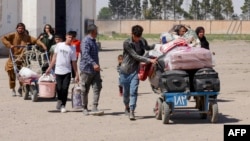 Əfqan qaçqınlar İrandan deportasiya edildikdən sonra əşyalarını daşıyırlar.