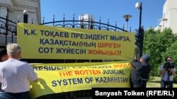 Жоғарғы сот төрағасымен кездесуді талап еткен бір топ адам ғимарат алдында nүнеп шықты. Солардың бірі Ильшат Кензин ғимарат маңындағы қоршауға баннер іліп жатыр. Нұр-Сұлтан, 16 маусым 2021 жыл.