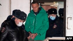 Aleksei Navalny is escorted out of a police station on January 18 in Khimki, outside Moscow.