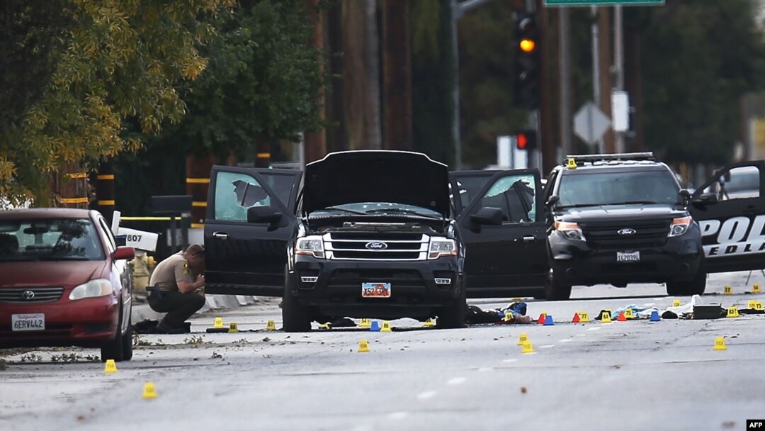 Law-enforcement officials investigate the Ford SUV vehicle that was the scene where suspects of the shooting at the Inland Regional Center were killed on December 3 in San Bernardino, California.