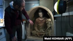 ارمانو کاربنارا، یک متخصص ایتالیایی ترمیم و مرمت مجسمه‌ها، در کنار مجسمه‌ی بودا یکی از آثار باستانی افغانستان، کابل، ۱۴ مارچ ۲۰۱۷ 