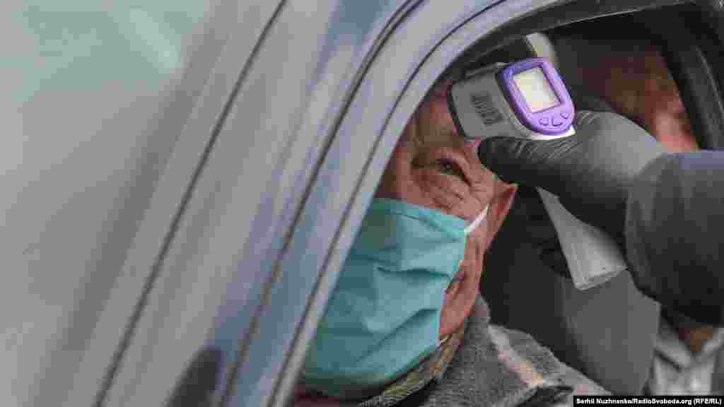 Медичний працівник вимірює водію температуру безконтактним способом на блокпосту на в&rsquo;їзді до міста Умань, 11 квітня 2020 року ФОТОРЕПОРТАЖ:&nbsp;Як перекрили в&rsquo;їзд в Умань через коронавірус