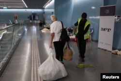 Израиль мен Иранның өзара атысты доғару келісімі күшіне енгеннен кейін, осыған дейін өзі паналаған жер астындағы теміржол станциясынан жүгін көтеріп шығып келе жатқан адам. Рамат-Ган, Израиль, 24 маусым, 2025 жыл.