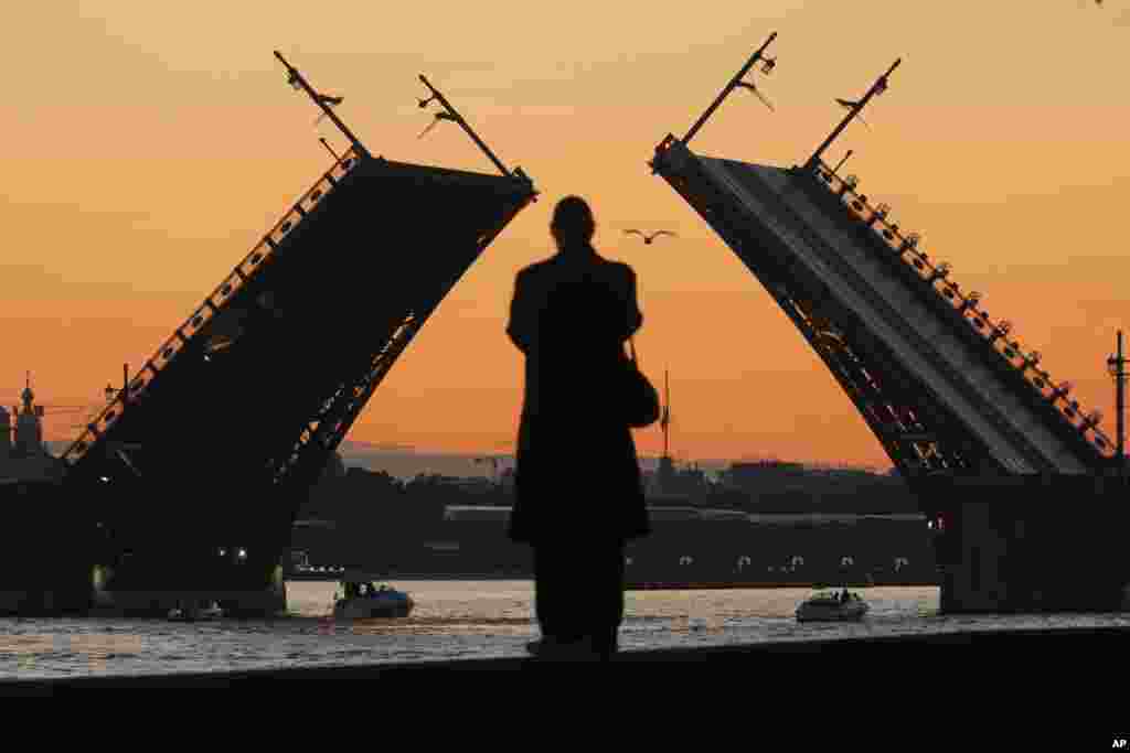 Санкт-Петербургдагы ачылып-жабылган көпүрөнү карап турган адам.