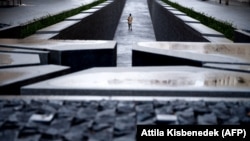 Молодий відвідувач гуляє по меморіалу Тріанонського договору біля будівлі парламенту в Будапешті в січні 2021 року