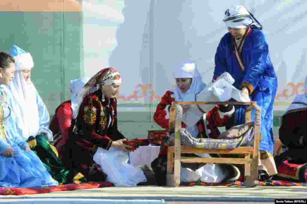 На сцене показывают обычай укладывания младенца в колыбель.