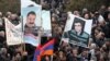 Armenia -- Demonstrators hold up pictures of jailed opposition members Aram Bareghamian (R) and Sasun Mikaelian, 1Mar2011.