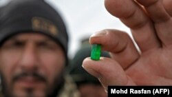 یک کارگر معدن در پنجشیر توته استخراج شده یی زمرد را نشان داده است