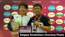 Кыз-келиндер күрөшү боюнча жаштар арасында Азиянын үч жолку чемпиону Мээрим Жуманазарова жана Кыргызстандын күрөш федерациясынын вице-президенти Байгазы Кенжебаев. Чонбури, Таиланд. 11-июль, 2019-ж.