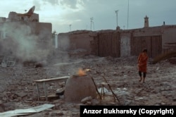 Местная жительница на фоне развалин идет к тандыру, традиционной печи для лепешек, после сноса жилого района Хивы, 2015 год. Сегодня на этом месте огороженный пустырь