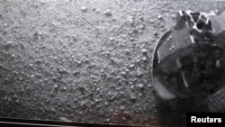 Көлүк-робот "Curiosity" Марстын бетине конор замат жөнөткөн фотосүрөттөн аппараттын бир дөңгөлөгү  көрүнүп турат. 6-август 2012