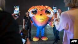 Наведнікі фатаграфуюцца з талісманам «Эўравізіі-2025» у Базэлі, 3 траўня 2025 году