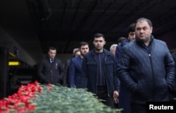 Азербайджанцы у мемориала, установленного возле аэропорта в Баку, в честь памяти жертв крушения пассажирского самолета Embraer