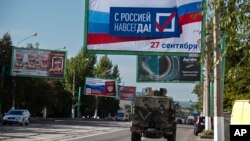 Російська військова машина і білборд із написом: «З Росією назавжди, 27 вересня» перед так званим референдумом, який Захід називає фіктивним, в окупованому Луганську