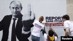 Активисты организации «Репортеры без границ» приклеивают плакат с изображением президента России Владимира Путина по случаю 20-ого ежегодного Всемирного дня свободы прессы. Париж, 3 мая 2013 года