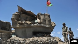 Afghan border policemen walk past a bunker, destroyed during recent clashes between Afghan border police and Pakistani troops in Goshta district of Nangarhar Province.