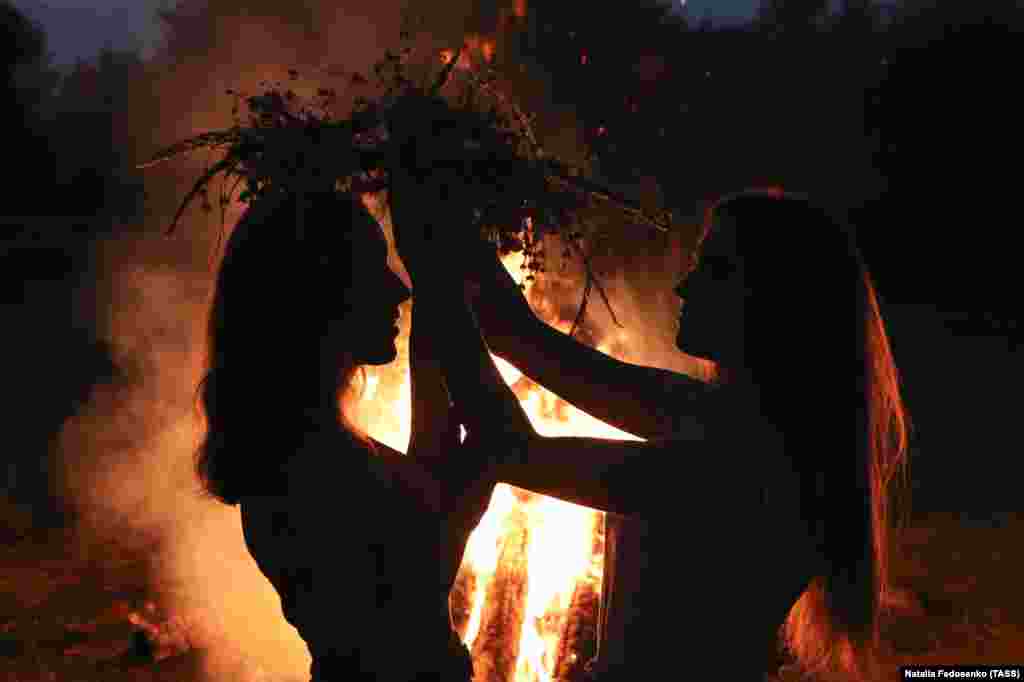 Дівчата одягають на голову вінки біля купальського&nbsp; багаття. Під час святкування Івана Купала на березі річки Прип&#39;ять. Білорусь, Гомельська область, 6 липня